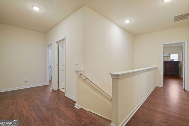 hallway featuring recessed lighting, visible vents, dark wood finished floors, and an upstairs landing