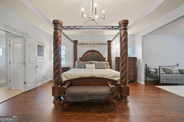 bedroom with a chandelier, dark wood-style flooring, and baseboards