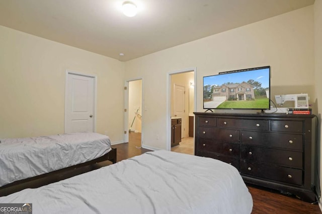 bedroom with baseboards, wood finished floors, and connected bathroom