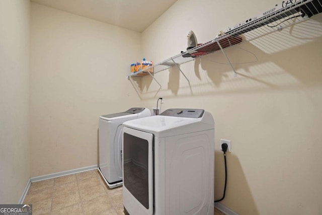 washroom featuring laundry area, washer and clothes dryer, and baseboards