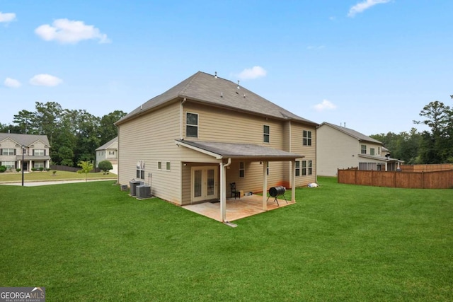 rear view of house featuring a patio, central AC, fence, and a lawn