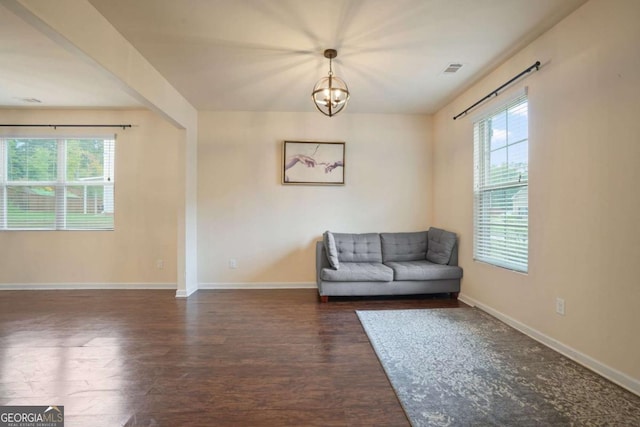 unfurnished room featuring an inviting chandelier, dark wood finished floors, visible vents, and baseboards