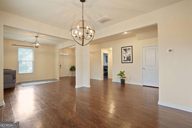 spare room with visible vents, dark wood finished floors, baseboards, and an inviting chandelier