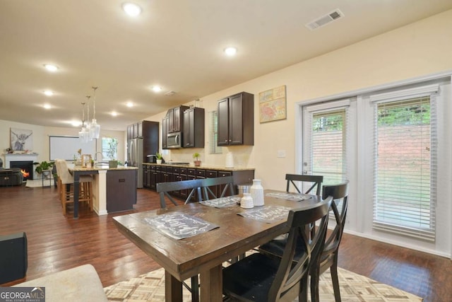 dining room with dark wood-type flooring, recessed lighting, visible vents, and a lit fireplace