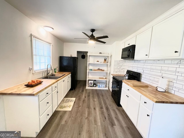 kitchen featuring wooden counters, black appliances, a sink, and white cabinets