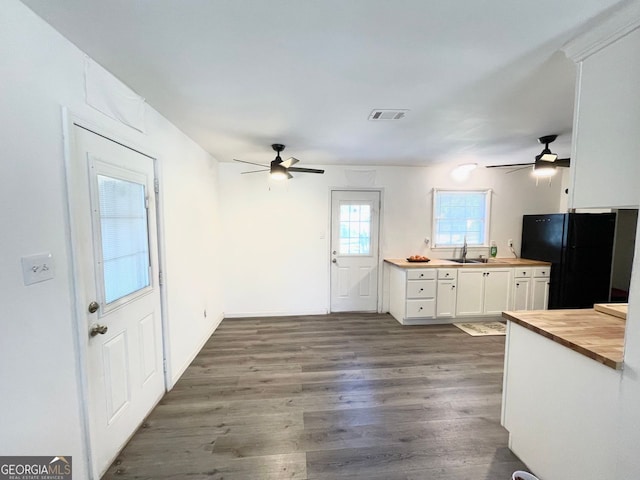 kitchen with visible vents, dark wood finished floors, wood counters, freestanding refrigerator, and white cabinetry