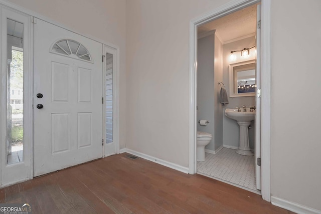 foyer entrance with visible vents, baseboards, and wood finished floors