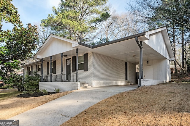 view of front of house featuring an attached carport, covered porch, brick siding, concrete driveway, and a front yard