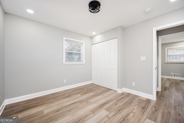 unfurnished bedroom featuring multiple windows, visible vents, and baseboards