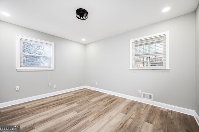 spare room with light wood finished floors, baseboards, visible vents, and a wealth of natural light