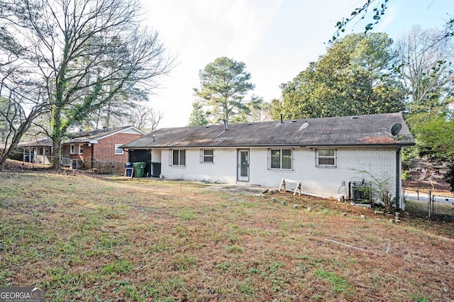 back of property featuring brick siding, fence, and a yard