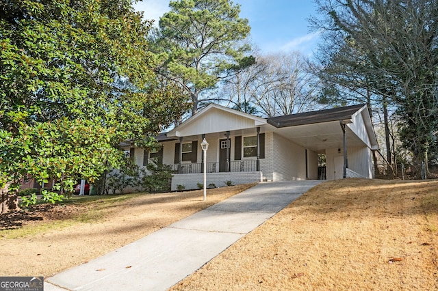 view of front of house with brick siding, covered porch, an attached carport, driveway, and a front lawn