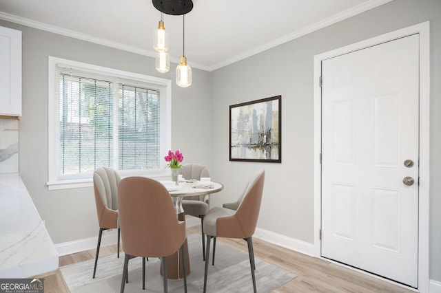 dining room featuring ornamental molding, light wood-type flooring, and baseboards