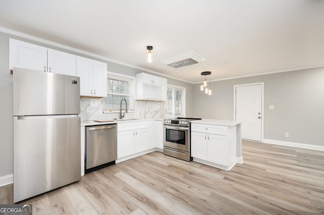 kitchen with a sink, white cabinets, light countertops, appliances with stainless steel finishes, and decorative light fixtures