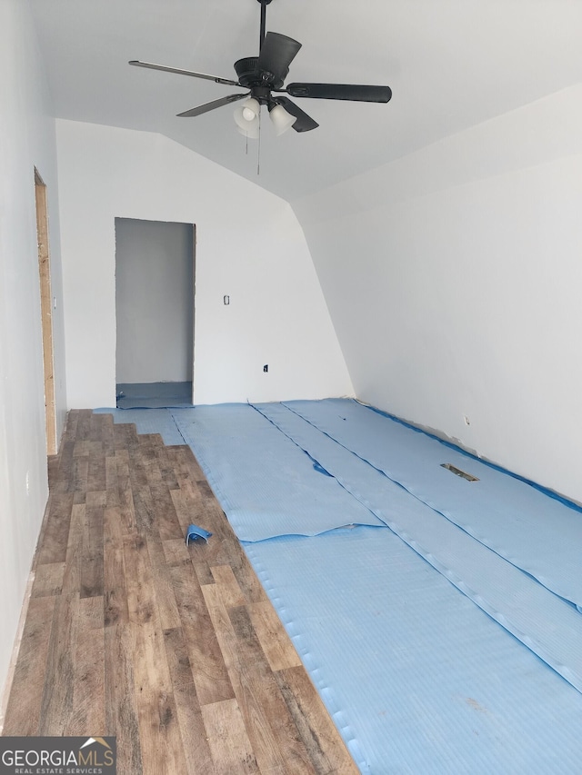 interior space with a ceiling fan, vaulted ceiling, and wood finished floors