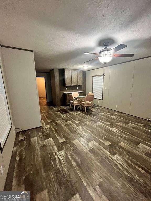 interior space featuring a ceiling fan, dark wood-style flooring, and a textured ceiling