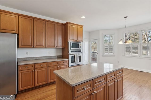 3690 Millwater Xing, Dacula, GA 30019 - kitchen with appliances with stainless steel finishes, brown cabinets, light wood finished floors, hanging light fixtures, and recessed lighting