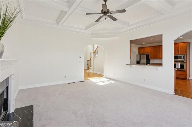 3690 Millwater Xing, Dacula, GA 30019 - unfurnished living room with arched walkways, a premium fireplace, ceiling fan, light colored carpet, and coffered ceiling