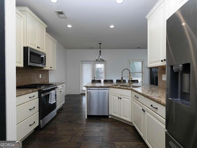 kitchen with stainless steel appliances, visible vents, white cabinets, hanging light fixtures, and light stone countertops