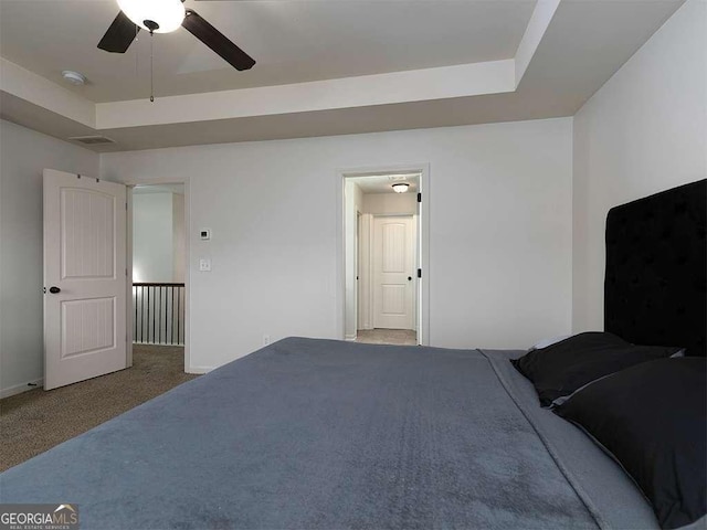 unfurnished bedroom featuring a tray ceiling, carpet flooring, ceiling fan, and baseboards