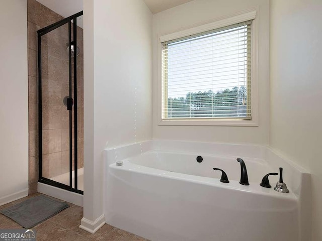 bathroom featuring a garden tub, a shower stall, baseboards, and tile patterned floors