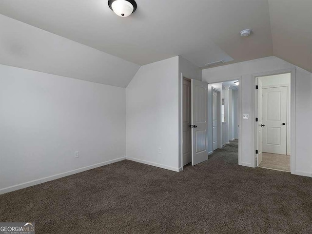 bonus room featuring dark colored carpet, lofted ceiling, and baseboards