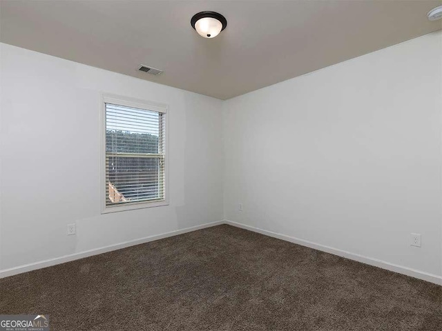 empty room featuring dark colored carpet and baseboards