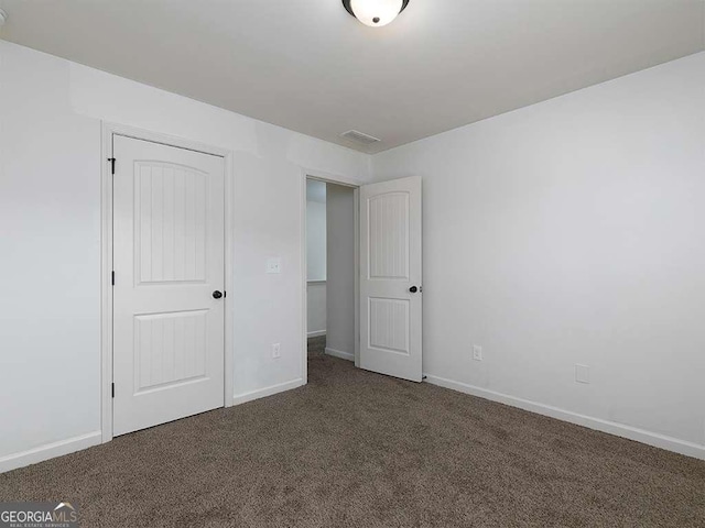 unfurnished bedroom with visible vents, baseboards, and dark colored carpet