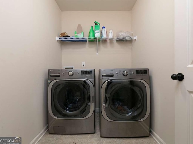 clothes washing area with laundry area, washing machine and dryer, and baseboards