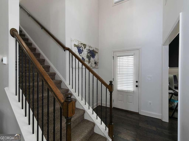 foyer with a towering ceiling, dark wood-style floors, and baseboards