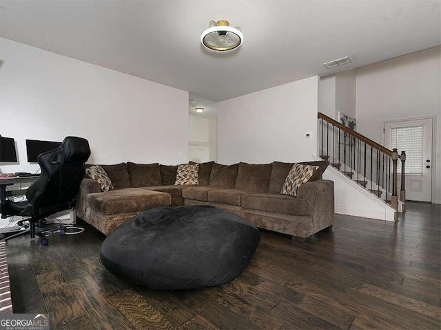 living room with dark wood-type flooring, stairway, and visible vents