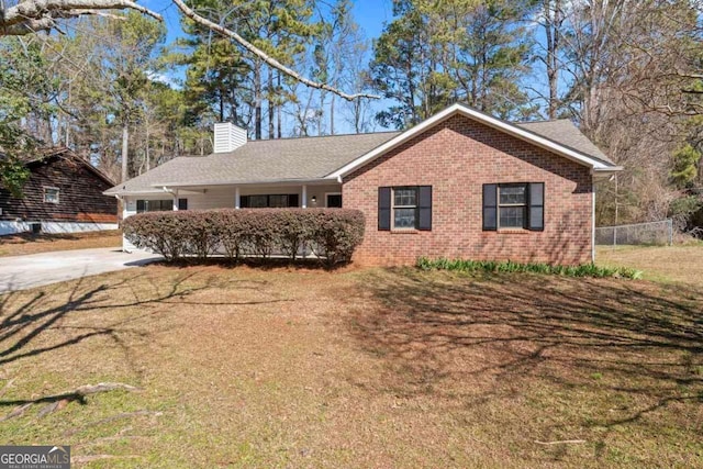 single story home with brick siding, a chimney, a front lawn, and fence