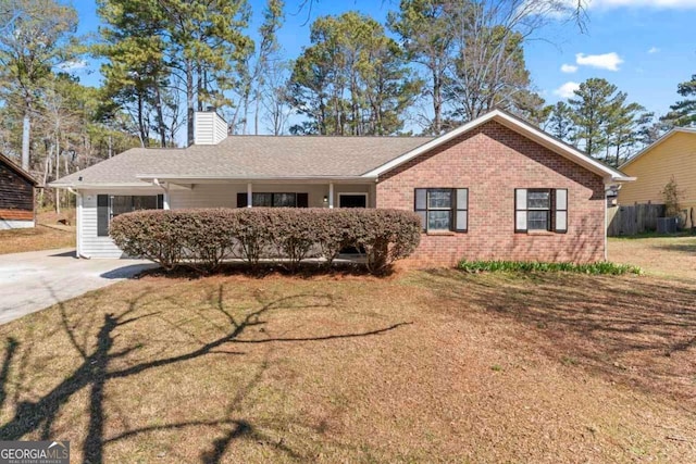 ranch-style house with a shingled roof, a front yard, brick siding, and a chimney