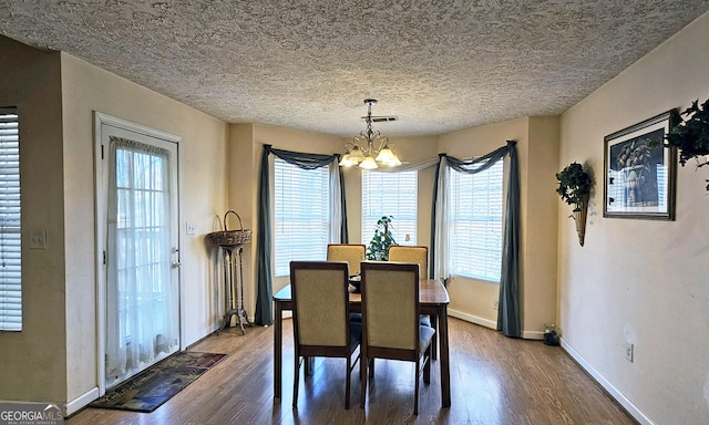 dining room with visible vents, plenty of natural light, an inviting chandelier, and wood finished floors