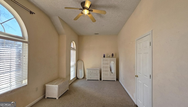 unfurnished bedroom featuring light carpet, multiple windows, a textured ceiling, and baseboards