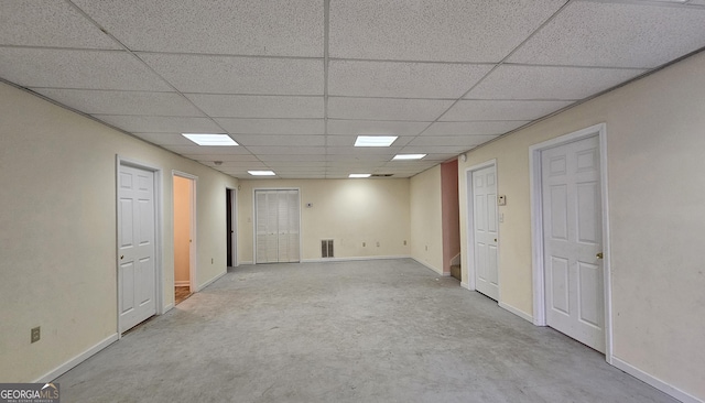 empty room with concrete flooring, a paneled ceiling, visible vents, and baseboards