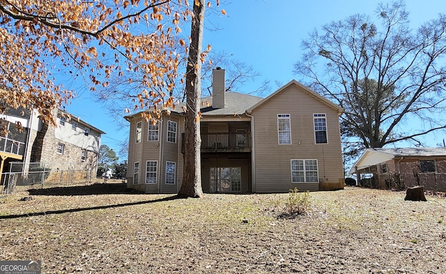 rear view of house with a chimney and fence