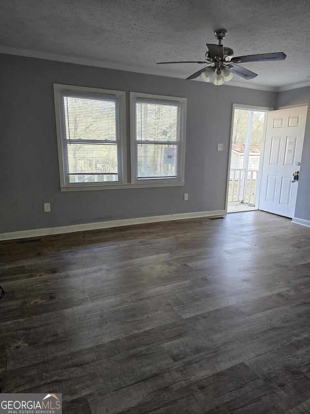 spare room featuring crown molding, a textured ceiling, baseboards, and dark wood-style flooring