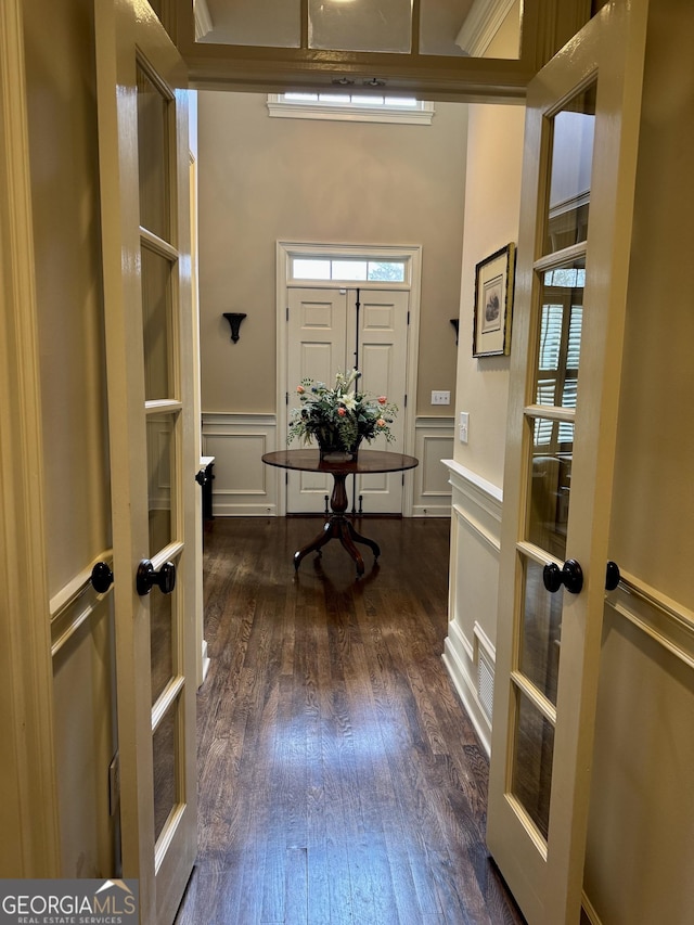 foyer entrance featuring dark wood-type flooring, french doors, and a decorative wall