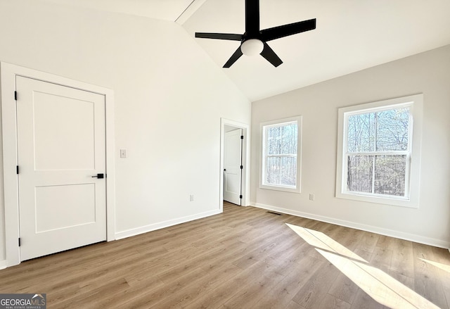 unfurnished bedroom featuring light wood finished floors, visible vents, baseboards, and high vaulted ceiling