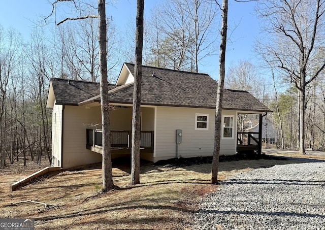 view of side of home with covered porch and roof with shingles