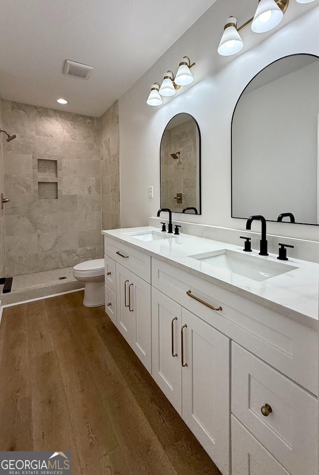 full bathroom featuring double vanity, wood finished floors, a sink, and visible vents