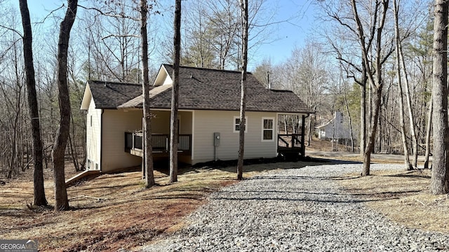 exterior space featuring roof with shingles and gravel driveway