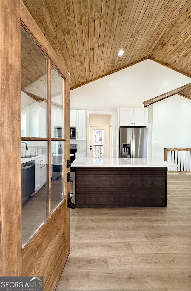 kitchen with vaulted ceiling, light countertops, appliances with stainless steel finishes, and white cabinetry