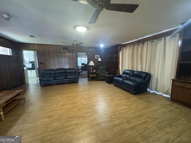 living area with visible vents, ceiling fan, a textured ceiling, and light wood finished floors