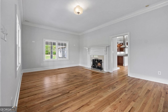 unfurnished living room with ornamental molding, a fireplace, baseboards, and wood finished floors