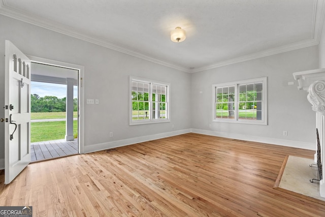 unfurnished living room featuring light wood-type flooring, a healthy amount of sunlight, baseboards, and crown molding