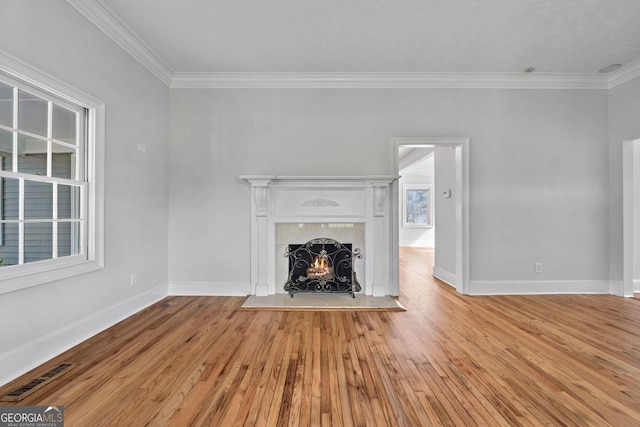 unfurnished living room featuring light wood-type flooring, a warm lit fireplace, baseboards, and visible vents