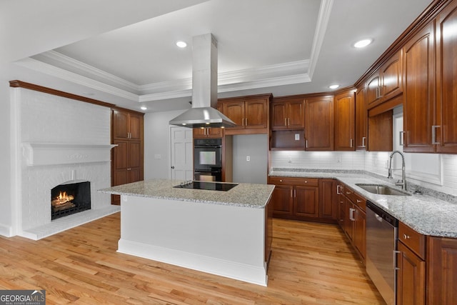 kitchen featuring a center island, island exhaust hood, a tray ceiling, black appliances, and a sink