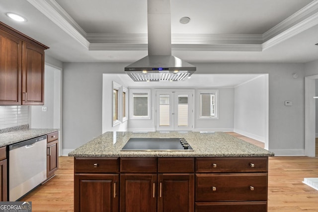 kitchen featuring a tray ceiling, island exhaust hood, black electric stovetop, light wood-style flooring, and dishwasher